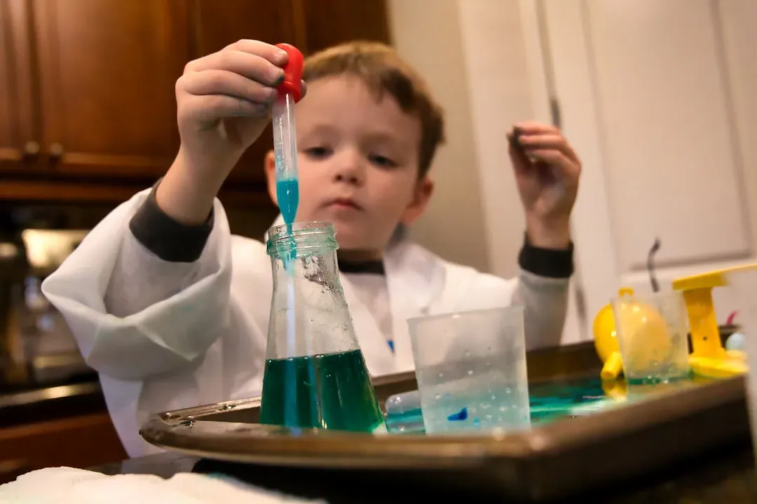 Child in safety goggles testing pH levels with color-coded strips in aquaponics system water for educational learning project