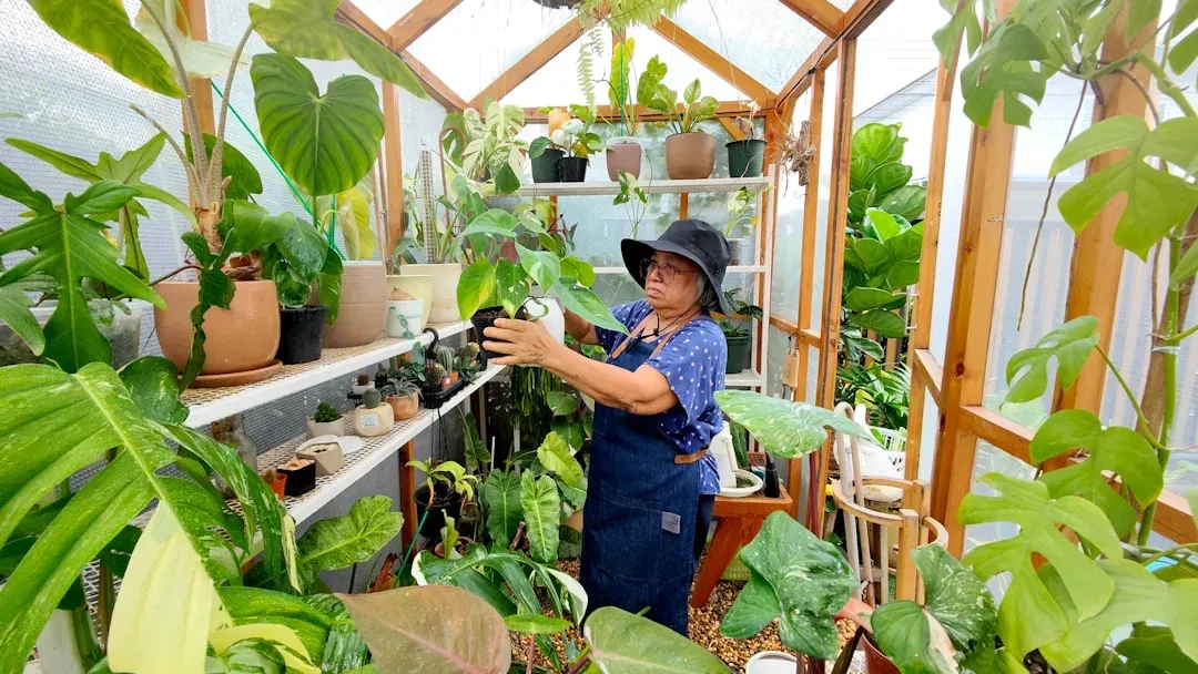 Gardener standing confidently in front of their aquaponics system with fish tanks and plants, demonstrating successful hydrop